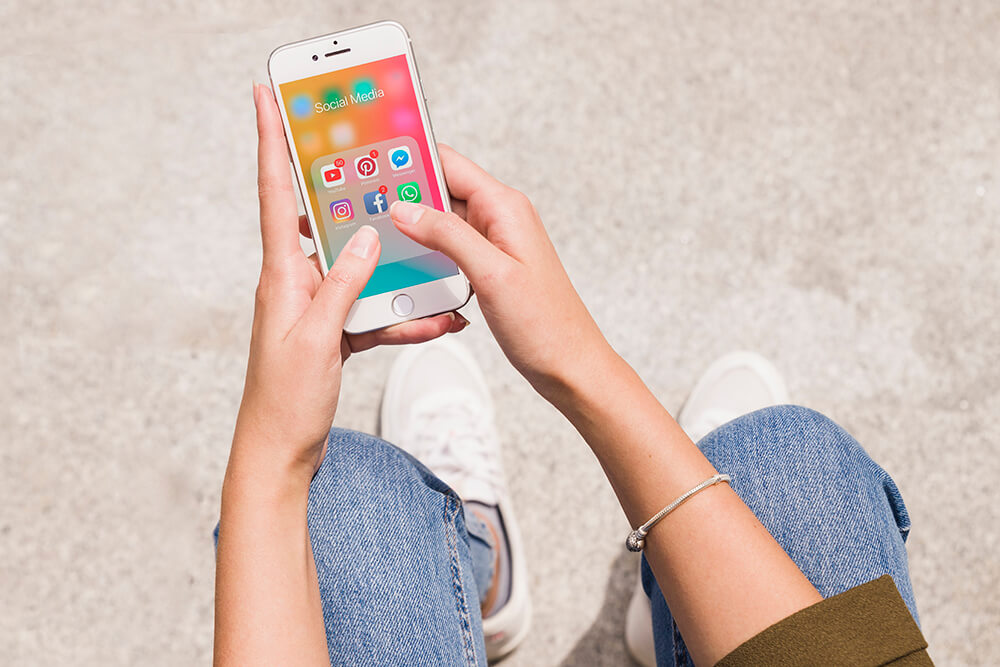 Top view of a woman holding a smartphone displaying different social media apps