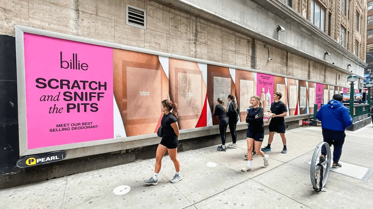 People passing by Billie’s Scratch and Sniff Armpit posters on the streets