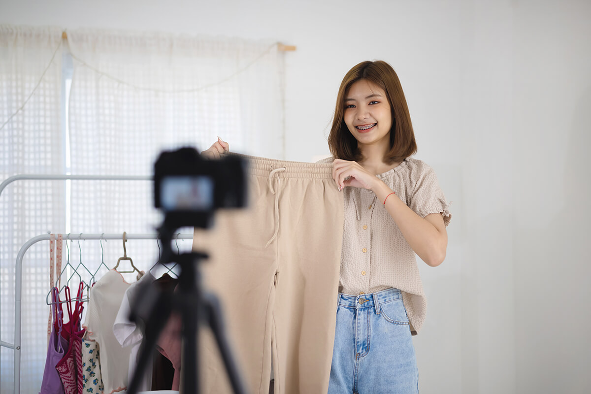 Young woman live-selling a pair of pants with a camera in front